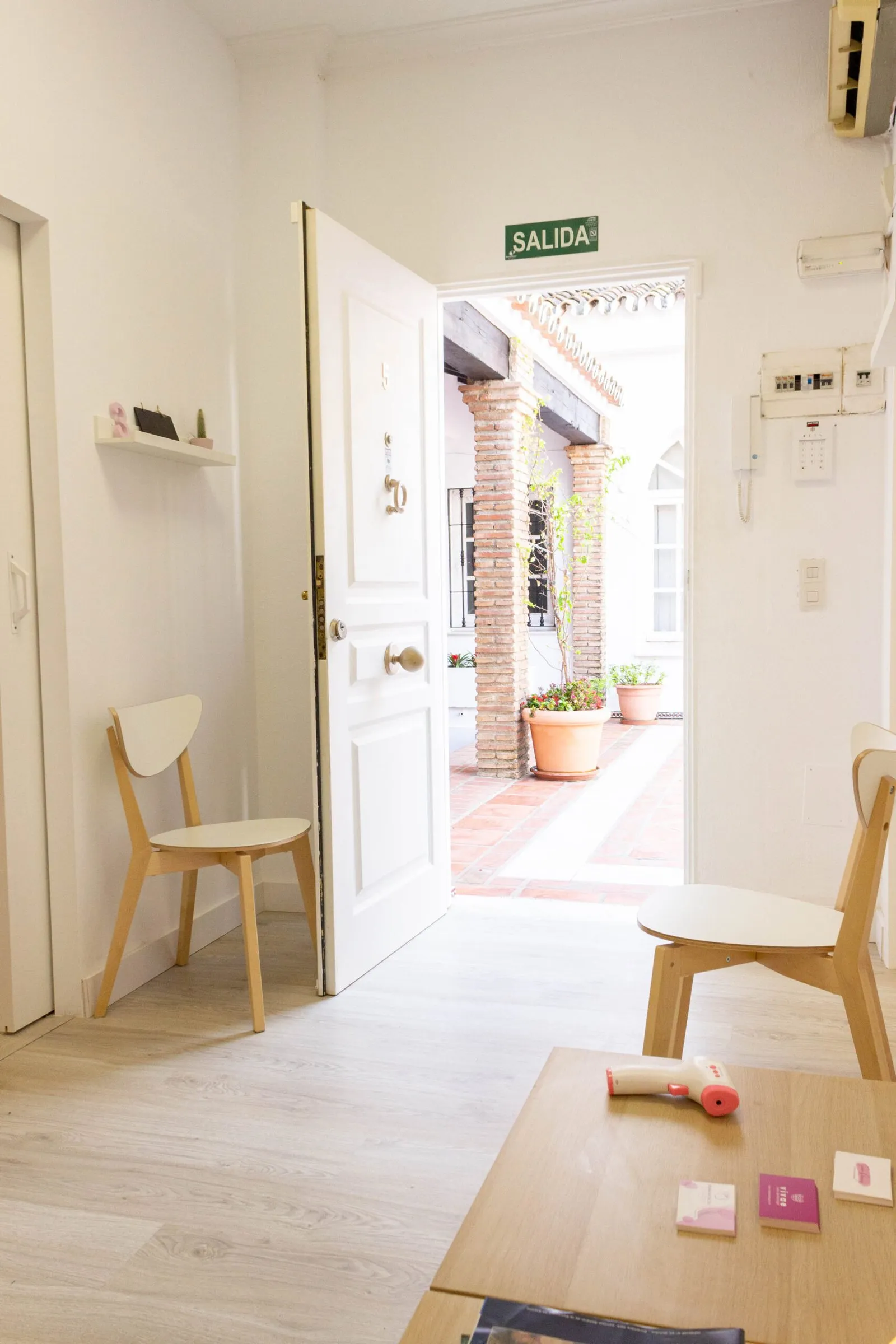 Entrada del centro con la puerta abierta al patio y sillas de madera