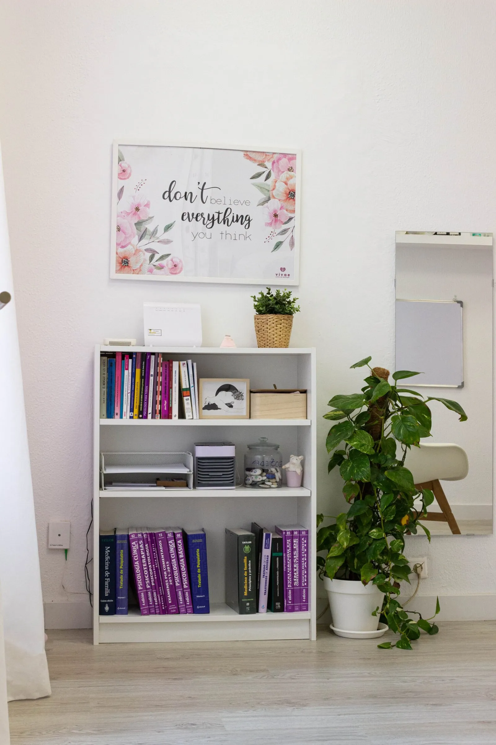 Estantería blanca con libros de psicología junto a una planta