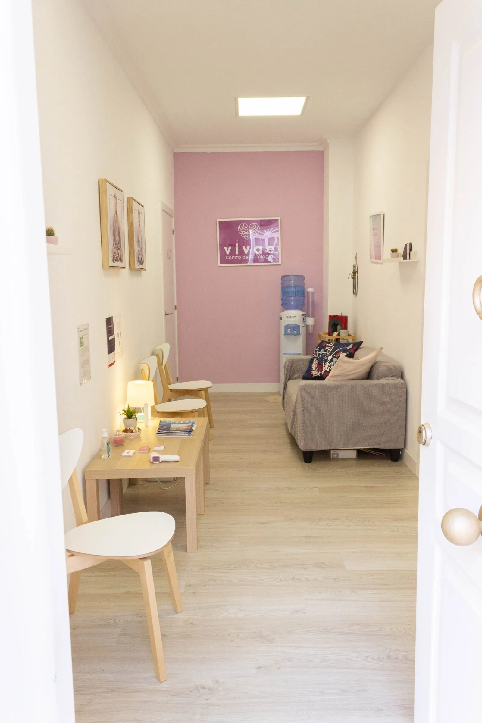 Pasillo del centro con sillas de madera que lleva a la sala de espera, con un sofá gris