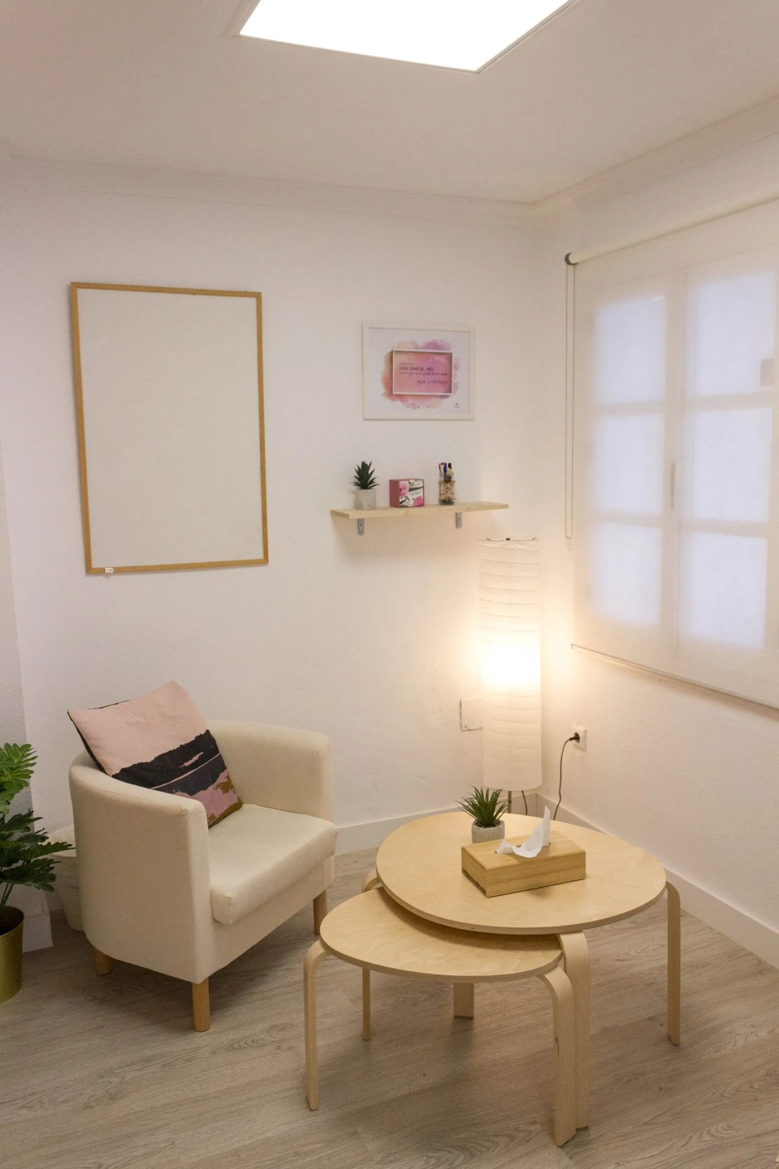 Sala de terapia con sillón, mesas redondas de madera y una lámpara encendida