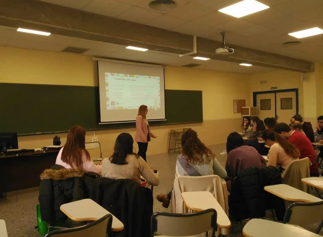 Sonia Ramírez de pie junto a la pantalla, impartiendo una clase en un aula
